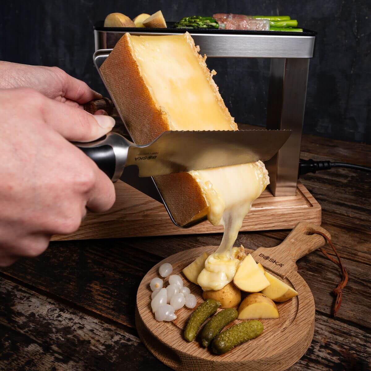 Raclette & Grill im Einsatz: geschmolzener Käse wird auf den Teller geschabt
